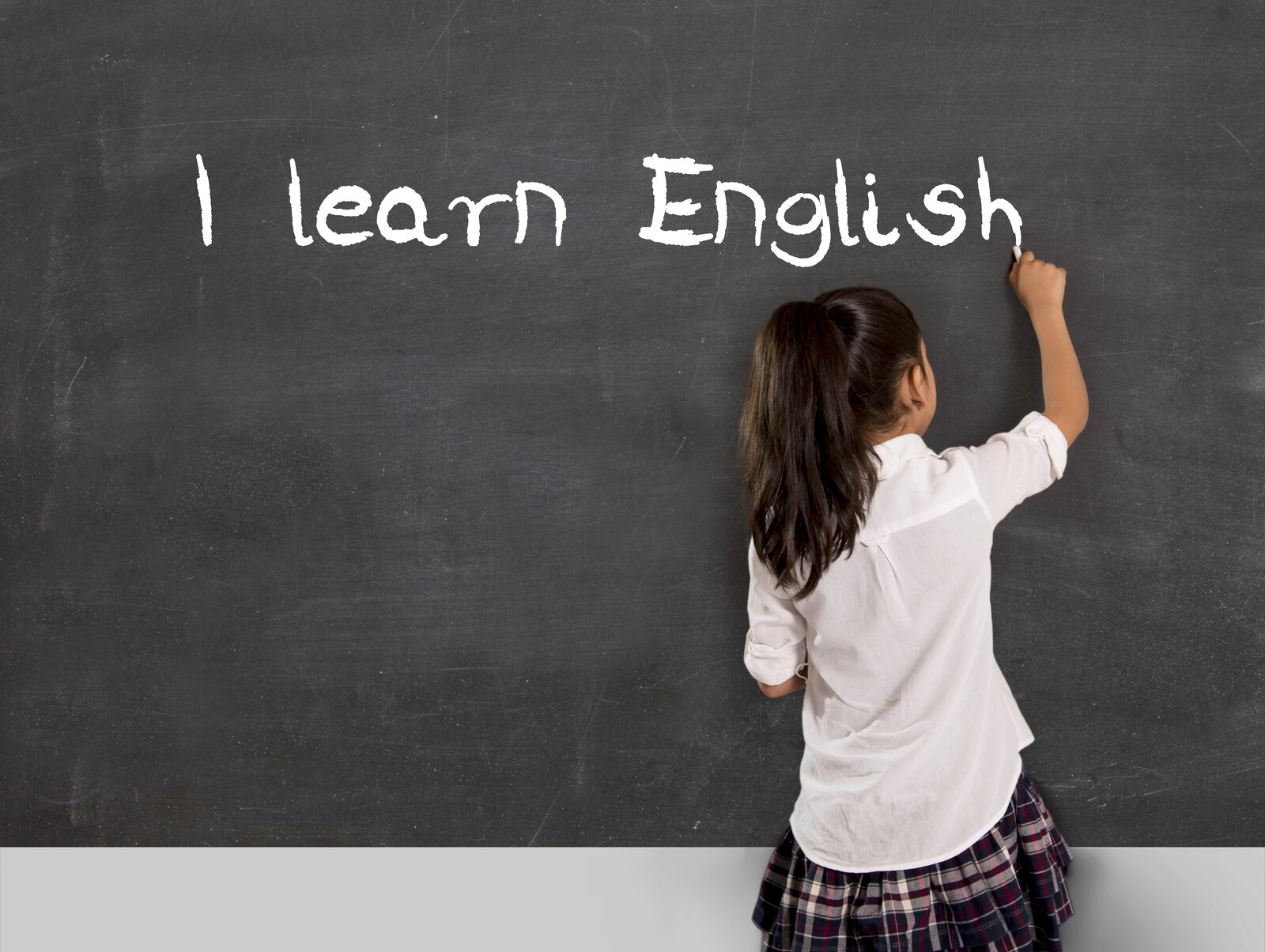 Alumna escribiendo I learn English en la pizarra