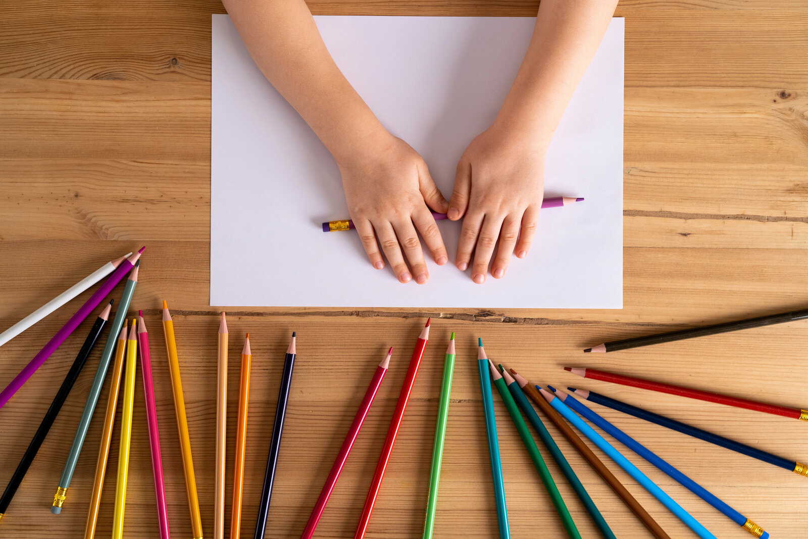 Manos infantiles dibujando con lápices de colores