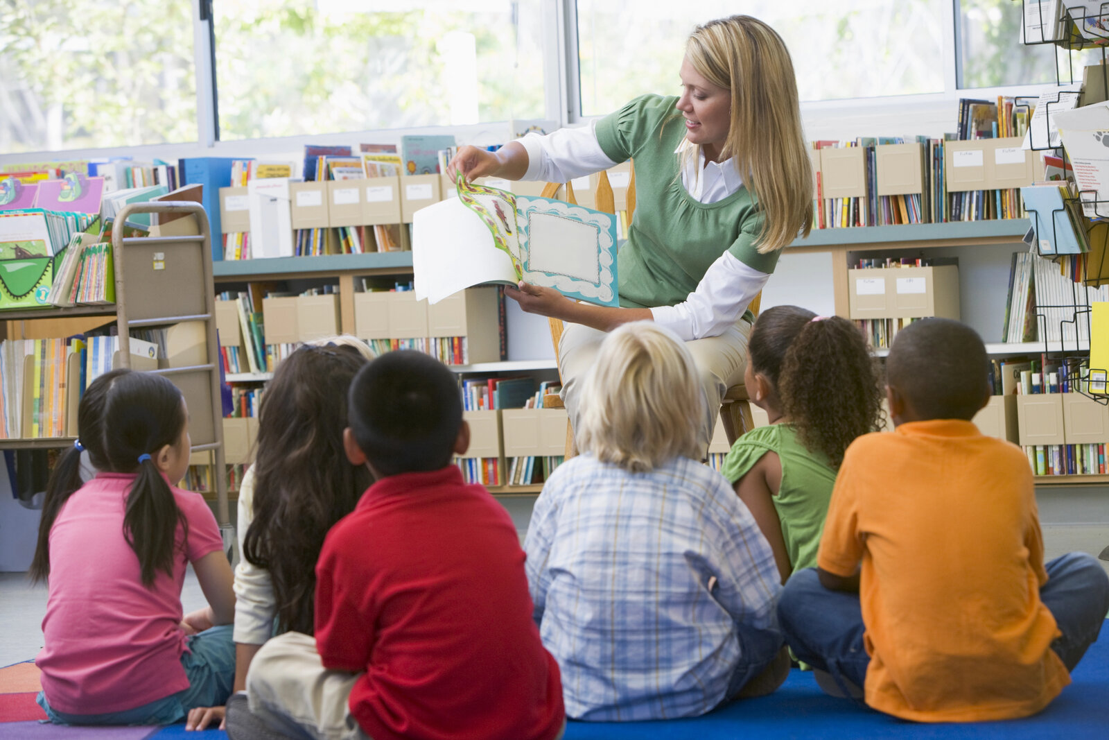 Profesora leyendo a un grupo de alumnos en la biblioteca