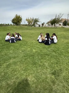 Alumnos trabajando en grupos al aire libre sobre el césped del colegio