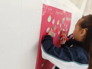 Alumna colocando adornos en un mural del aula