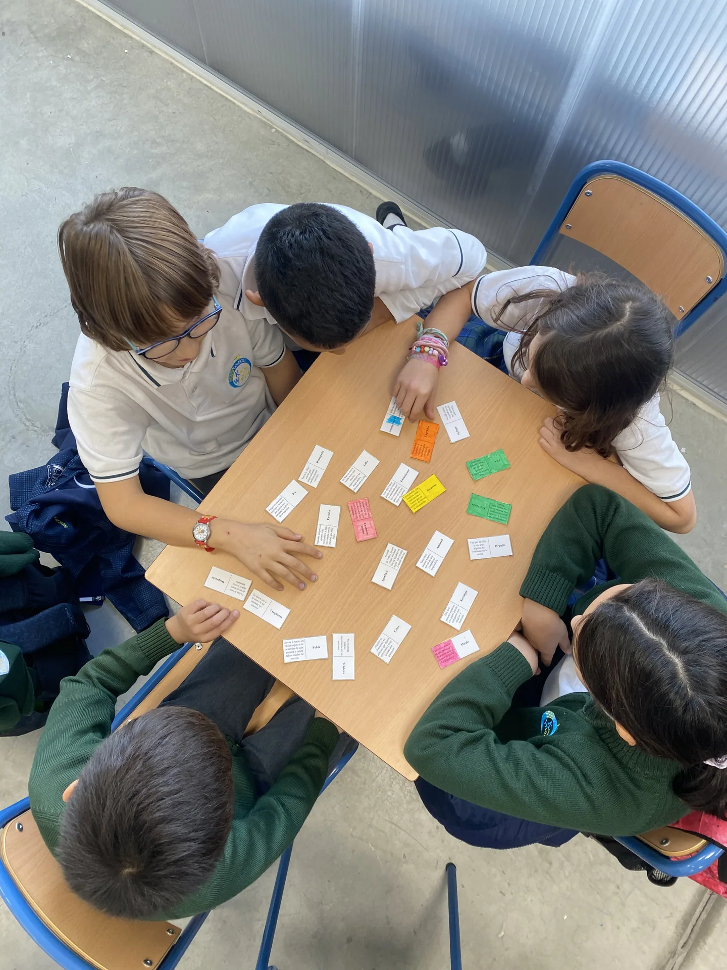 Alumnos trabajando en equipo alrededor de una mesa en clase