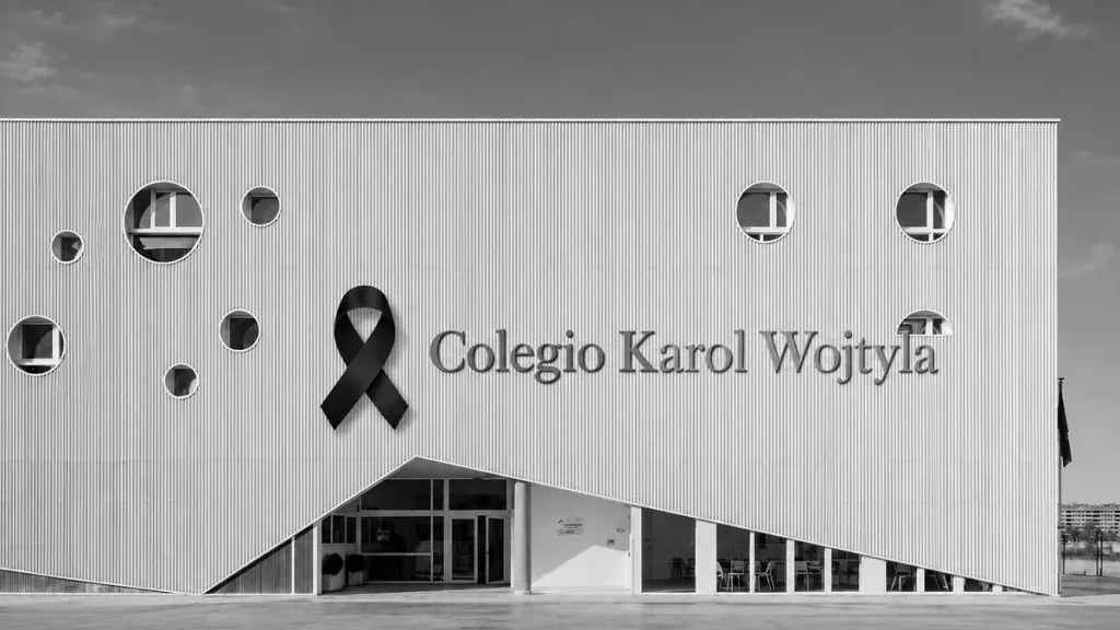 Fachada del Colegio Karol Wojtyla en blanco y negro con un lazo negro de luto junto al nombre del colegio